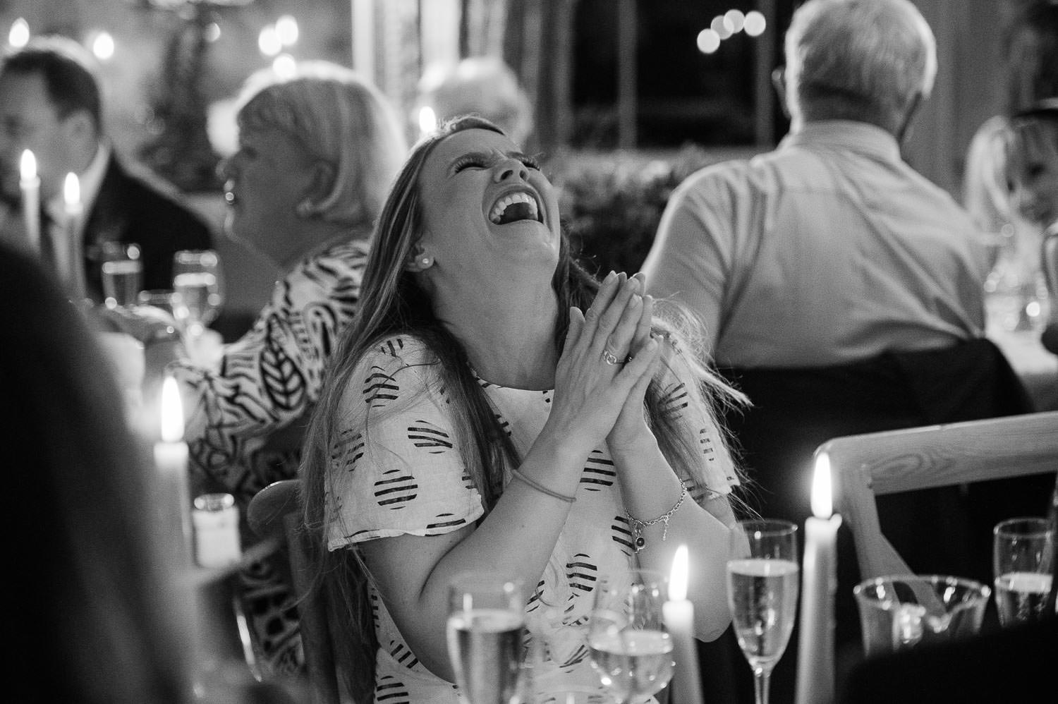 A wedding guest laughing at the groom's speech. 