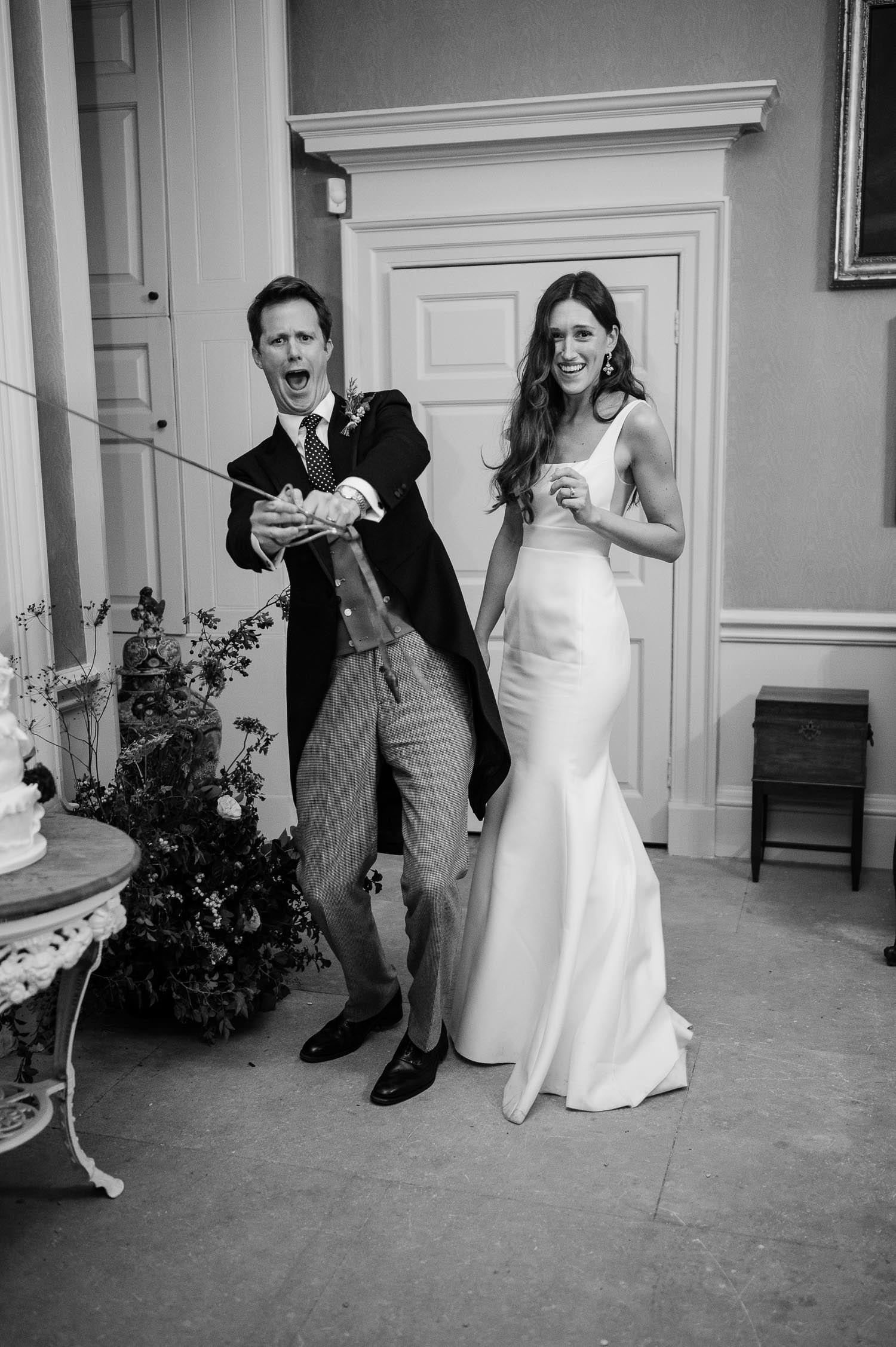 The couple cutting the cake with a sward.